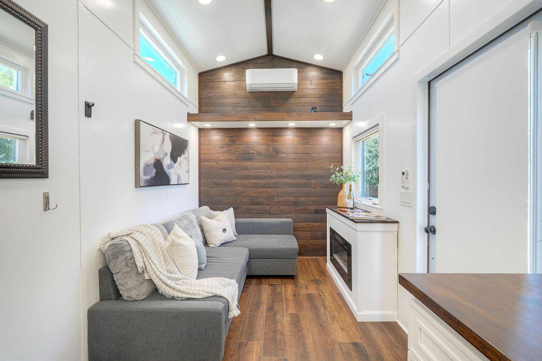 Interior of a compact ADU with a vaulted ceiling, wood accent wall, and built-in fireplace