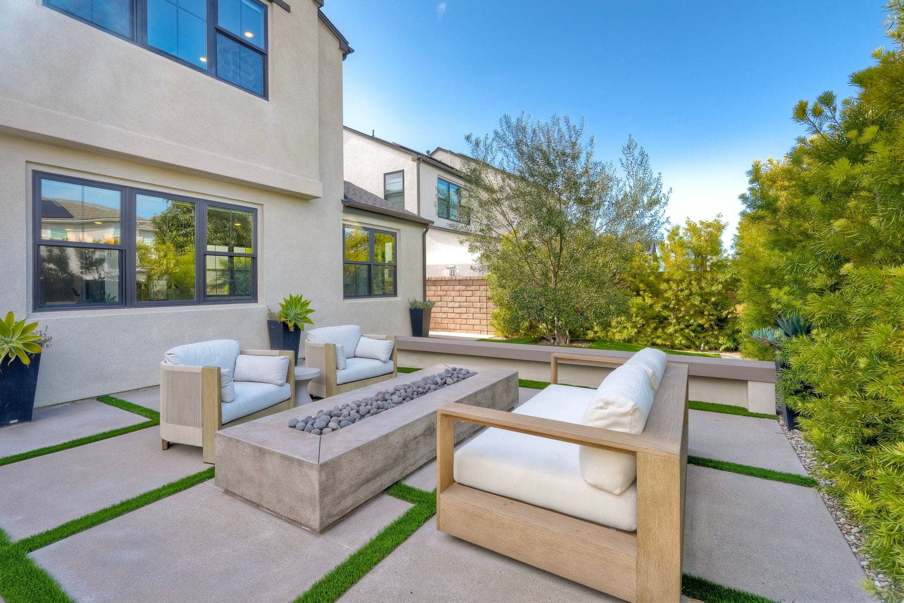 Backyard patio with a concrete fire pit table and lounge seating
